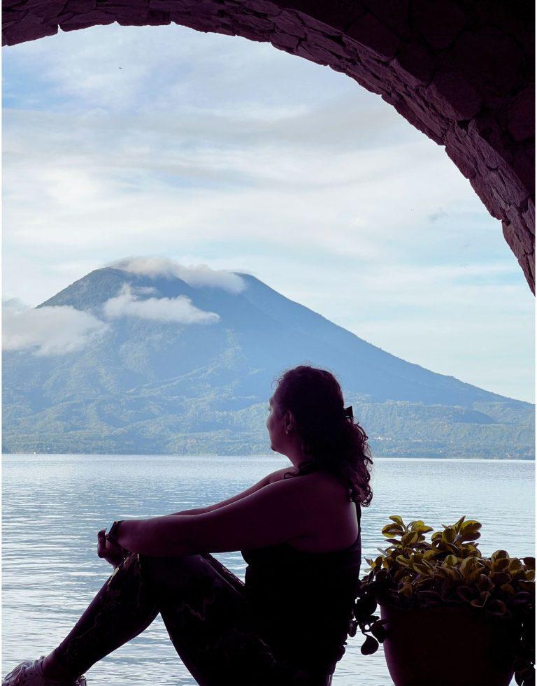 Woman - the author - sitting contemplating Lake Atitlan during Blue hour. This article is about changing your solo travel mindset.