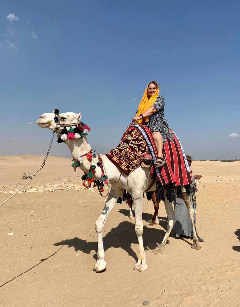 Latina Mom solo travels. She is sitting on a camel in Egypt.