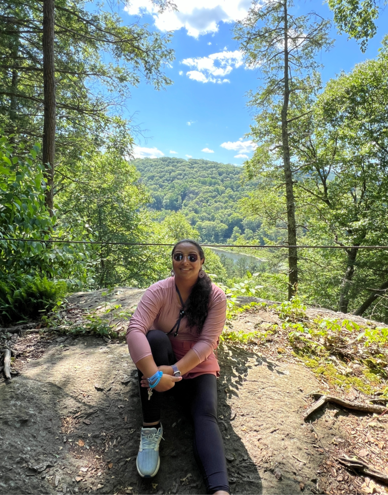 Woman sitting on a ledge. Camp Indie / Club. Getaway grounds in Berkshire Mountains, Kent, CT in the background.