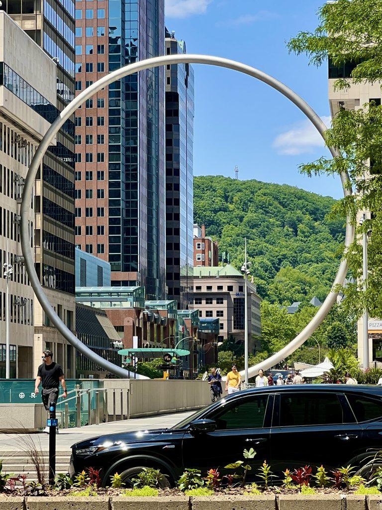 Place Ville Marie and The Ring sculpture in downtown Montréal with Mount Royal in the background, featured in The Queen of Trips guide on where to stay in Montréal 2026.