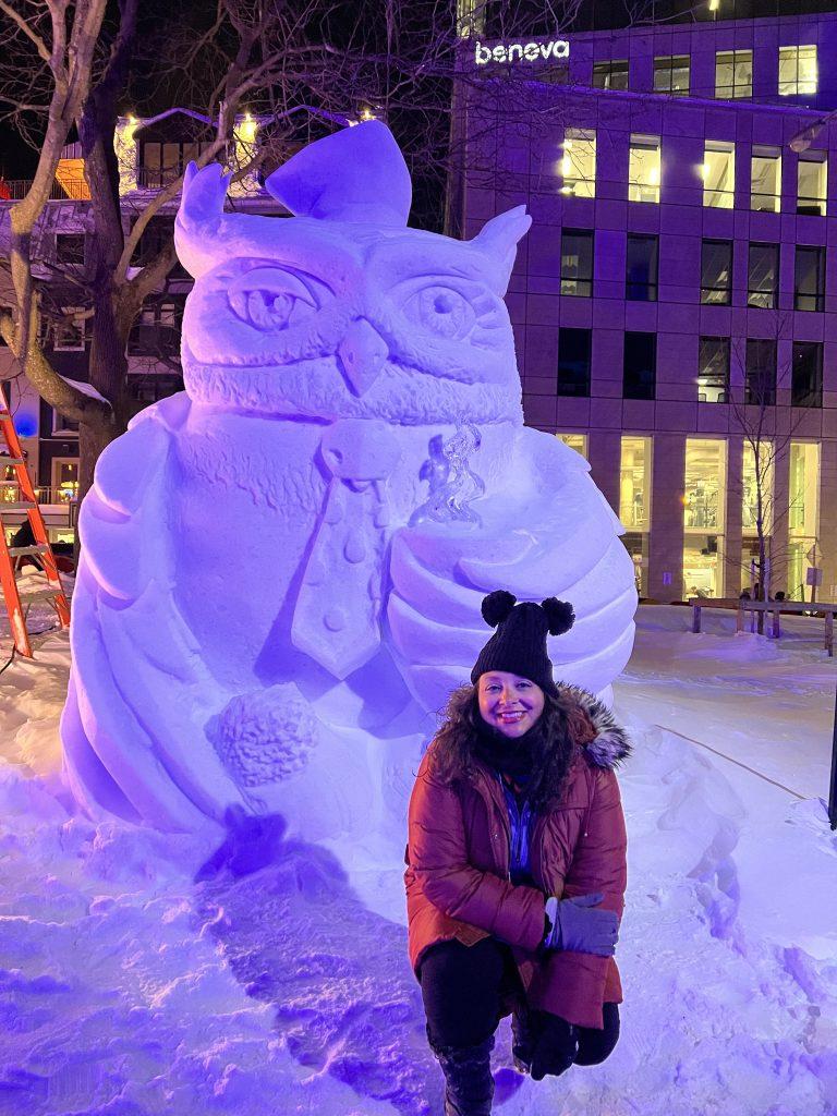 Solo female traveler posing in front of a snow sculpture at Quebec Winter Carnival in Quebec City